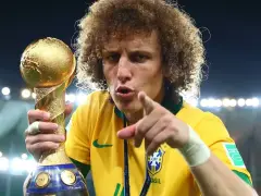 Piłkarz z Brazylii, z bujną fryzurą, triumfalnie trzyma złoty puchar Konfederacji FIFA.