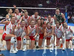 Uśmiechnięte polskie siatkarki w biało-czerwonych strojach pozują do zdjęcia po meczu, dumne ze zwycięstwa.