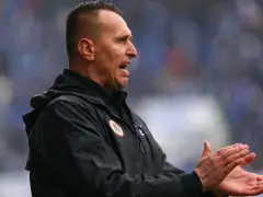 Trener Zagłębia Lubin, w czarnej kurtce, z otwartymi ustami i klaszczącymi dłońmi, motywuje drużynę.