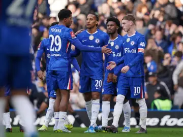 Piłkarze Chelsea w niebieskich strojach rozmawiają na boisku. Widać numery 29, 20 i 10.