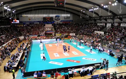 Widownia kibicuje podczas meczu siatkówki ZAKSA. Pełna hala, zawodnicy na boisku, emocje sięgają zenitu.