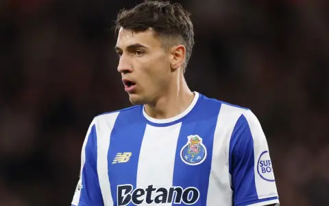 Piłkarz w niebiesko-białej koszulce FC Porto, gdzie gra Kiwior, z uwagą obserwuje boisko.