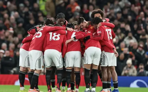 Piłkarze Manchesteru United w czerwonych strojach tworzą zwarty krąg, jednocząc się przed meczem. Ich wspólne united transfery budują ducha drużyny.
