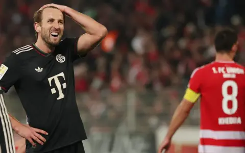 Piłkarz Bayernu w czarnej koszulce z T na piersi, z ręką na głowie, w meczu przeciwko Union Berlin.