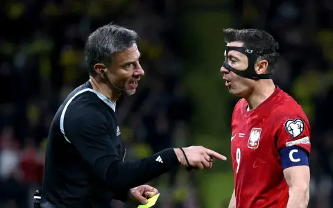 Sędzia pokazuje żółtą kartkę Robertowi Lewandowskiemu, jednej z legend piłki nożnej.