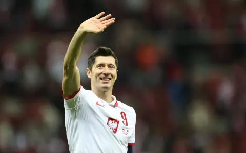 Robert Lewandowski w koszulce reprezentacji Polski z numerem 9, macha do kibiców.