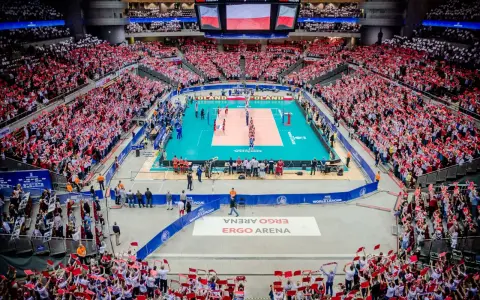 Widownia Ergo Areny, wypełniona kibicami z flagami Polski, dopingująca mecz siatkówki. Ogromna pojemność hali robi wrażenie.