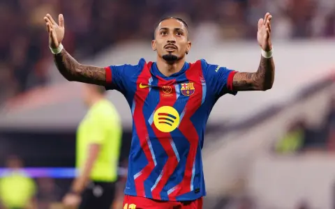 Raphinha, z podniesionymi rękami, świętuje po dołączeniu do FC Barcelony. Jego koszulka zdobi logo Spotify.