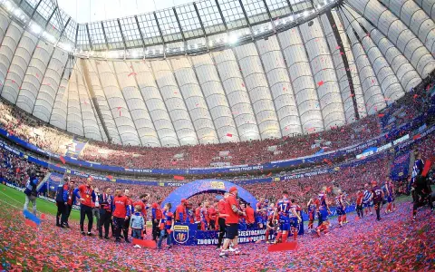 Piłkarze świętują zdobycie STS Pucharu Polski na murawie stadionu, zasypani czerwonymi konfetti.