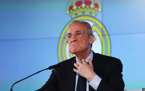 Florentino Pérez, prezes Realu Madryt, w garniturze, z ręką na szyi, na tle logo klubu.