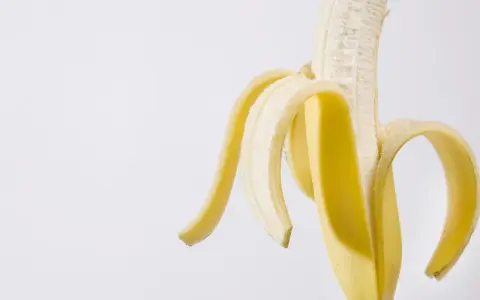 Połówka obranego banana, idealna przekąska przed czy po treningu, dostarcza energii.