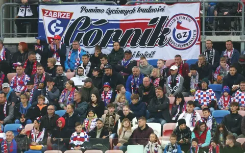 Tłum kibiców Górnika Zabrze, w szalikach i barwach klubowych, wspiera drużynę.