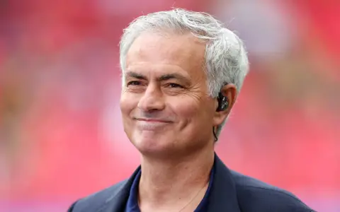 Uśmiechnięty José Mourinho, były trener Realu Madryt, z siwymi włosami i słuchawką w uchu.