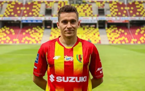 Piłkarz Korony Kielce w czerwono-żółtej koszulce na tle stadionu. Czekamy na kolejne transfery Korona Kielce!
