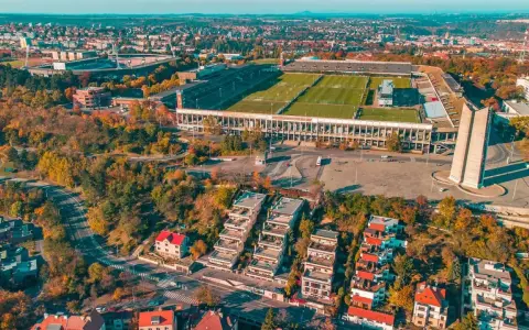 Widok z lotu ptaka na imponujący stadion, największy stadion w Europie, otoczony jesienną zielenią i nowoczesną zabudową.