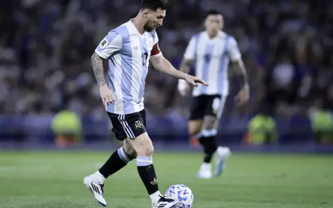 Lionel Messi w koszulce Argentyny prowadzi piłkę, gotowy do zdobycia kolejnych bramek. Fani zastanawiają się, ile goli ma Messi.