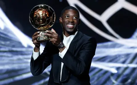 Piłkarz Ousmane Dembélé trzyma Złotą Piłkę na scenie.