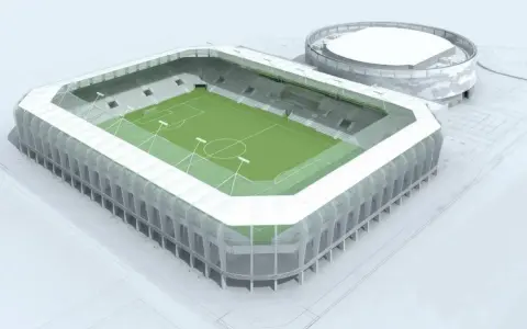 Nowoczesny stadion RKS Radomiak Radom z zieloną murawą i trybunami. Obok okrągły budynek.