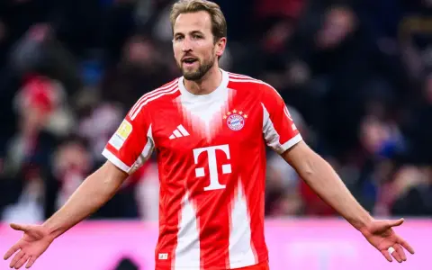 Piłkarz Harry Kane w czerwonej koszulce Bayernu Monachium, zastanawia się, ile zarabia.