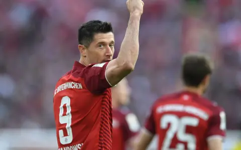 Piłkarz Robert Lewandowski w czerwonej koszulce z numerem 9 świętuje bramkę.