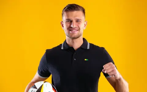 Uśmiechnięty piłkarz z piłką, symbolizujący nowe transfery GKS Katowice.
