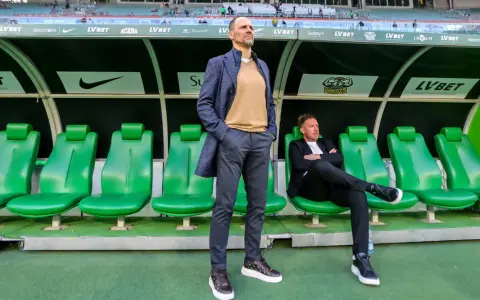 Trener Śląska Wrocław Ivan Djurdjevic stoi na tle zielonych siedzeń rezerwowych.