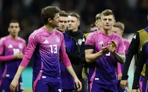 Piłkarze reprezentacji Danii i Niemiec w różowo-fioletowych strojach.