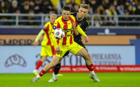 Piłkarz w żółto-czerwonej koszulce walczy o piłkę z rywalem w czarnym stroju. Intensywny przebieg: Pogoń Szczecin – Korona Kielce.