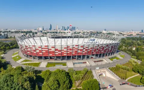 PGE Narodowy, jeden z największych stadionów w Polsce, w otoczeniu zieleni i warszawskiej panoramy.