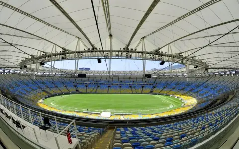 Pusta Marakana, stadion w Rio de Janeiro, z zieloną murawą i żółto-niebieskimi siedzeniami pod białym dachem.