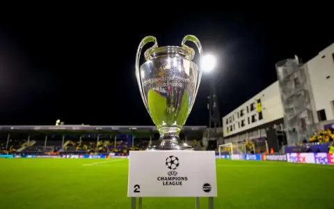 Puchar Ligi Mistrzów na tle stadionu. Ile drużyn awansuje do ligi mistrzów? To pytanie zadają sobie kibice.