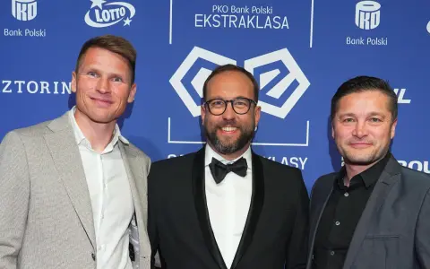 Trzech mężczyzn na tle PKO Bank Polski Ekstraklasa. Jeden z nich, w garniturze, uśmiecha się do obiektywu, być może jako jeden z przyszłych królowie strzelców ekstraklasy.