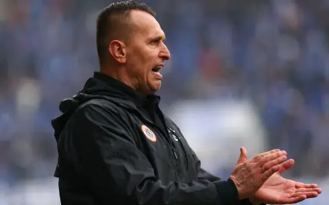 Trener Zagłębia Lubin, w czarnej kurtce, z otwartymi ustami i klaszczącymi dłońmi, motywuje drużynę.