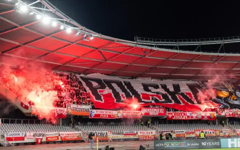 Tłum kibiców, ultrasi, tworzy morze czerwonego dymu i ognia, rozwijając ogromny transparent "POLSKA".