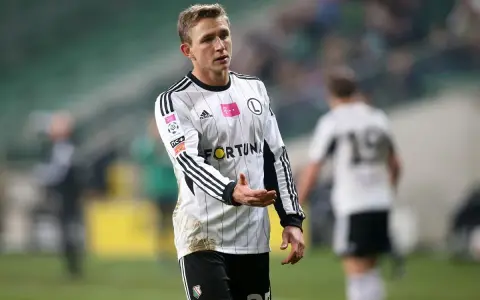 Kuba Rzeźniczak w białej koszulce z czarnymi pasami, na boisku.