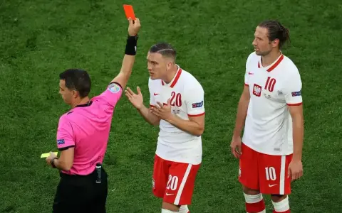 Sędzia pokazuje czerwoną kartkę w siatkówce. Piłkarz z numerem 20 protestuje, obok stoi kolega z numerem 10.