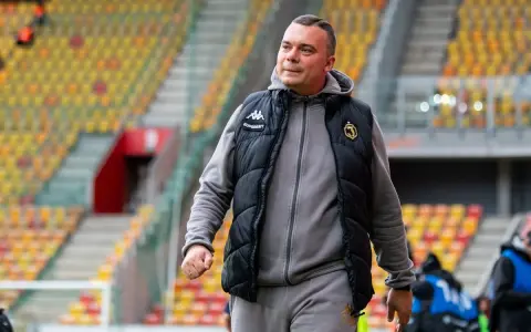 Mężczyzna w kamizelce Jagiellonii, być może omawia nowe jagiellonia transfery na tle pustych trybun stadionu.