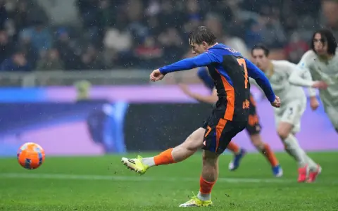 Piłkarz w niebiesko-czarnej koszulce z numerem 7 strzela gola w deszczu podczas meczu Inter Mediolan – AS Roma.