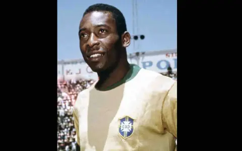 Uśmiechnięty Pelé w żółtej koszulce z herbem Brazylii. Jego niesamowite pelé statystyki mówią same za siebie.