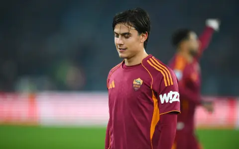 Piłkarz AS Roma w bordowej koszulce z pomarańczowymi pasami, gotowy do gry przeciwko Atalancie.