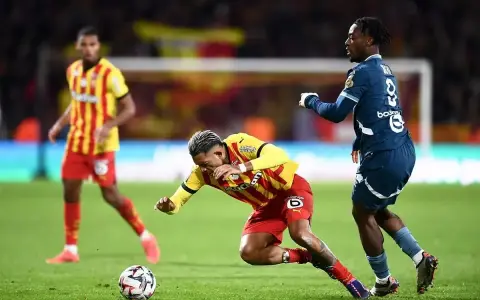 Piłkarz RC Lens w żółto-czerwonym stroju walczy o piłkę z zawodnikiem Stade Rennais.