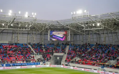 Widownia na stadionie Odra Opole podczas meczu otwarcia. Kolorowe trybuny i wielki ekran z napisem "Mecz otwarcia Itaka Areny".