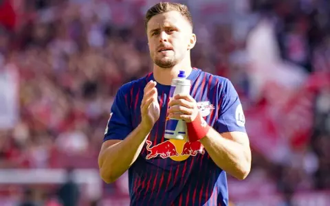 Piłkarz w koszulce RB Leipzig, jeden z zawodników 2. Bundesligi, trzyma butelkę z napojem.