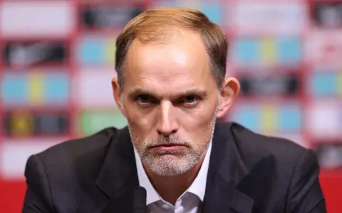 Thomas Tuchel, były trener Chelsea, z poważną miną przed mikrofonem.