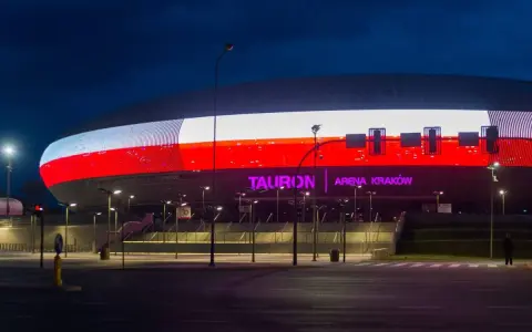 Tauron Arena Kraków nocą, z podświetloną fasadą w barwach narodowych. Obiekt mieści 15 tysięcy widzów, co czyni go jednym z największych w Polsce.
