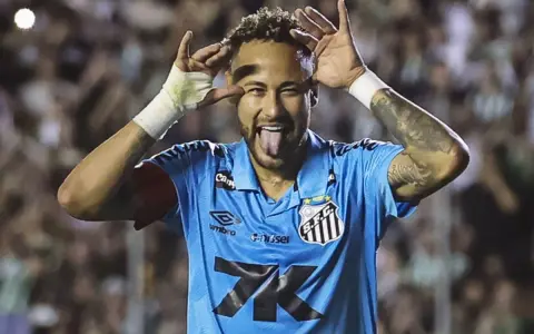 Neymar w niebieskiej koszulce Santos z charakterystycznym gestem i wystawionym językiem. Tak wygląda boisko, gdzie gra Neymar.