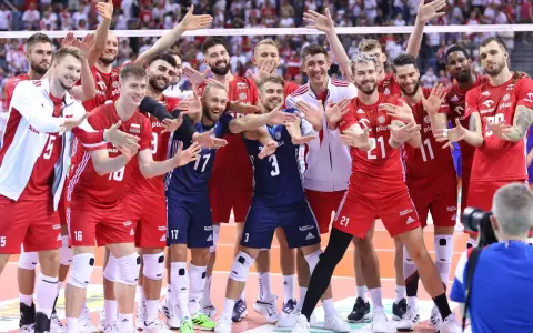 Uśmiechnięci siatkarze polski w czerwonych strojach pozują do zdjęcia, ciesząc się zwycięstwem.