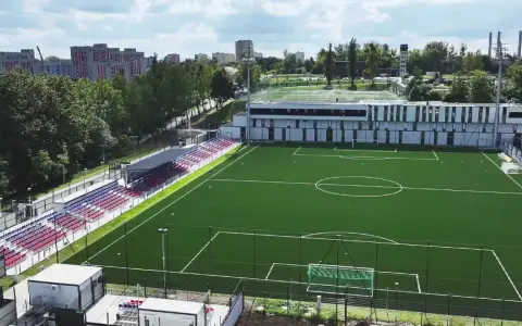 Nowy stadion Polonii Bytom z zieloną murawą, trybunami w kolorach czerwonym i niebieskim oraz nowoczesnym budynkiem klubowym.