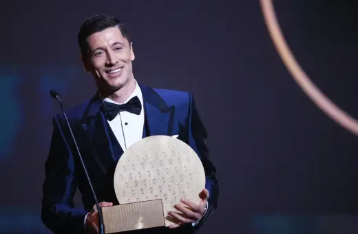 Uśmiechnięty Robert Lewandowski w eleganckim garniturze odbiera nagrodę, być może Złotą Piłkę.