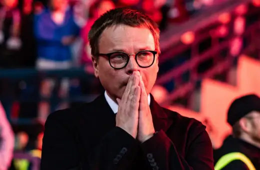 Właściciel Wisły Kraków, w okularach, z rękami złożonymi do modlitwy, wpatruje się w dal.